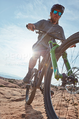 Buy stock photo Cropped shot of an athletic man mountain biking through the wilderness