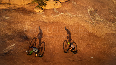 Buy stock photo High angle shot of two young male athletes mountain biking in the wilderness