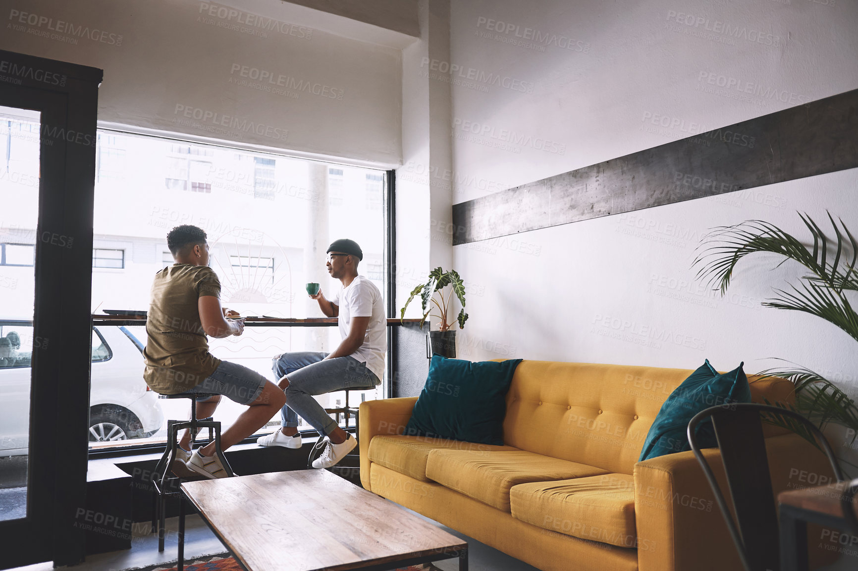 Buy stock photo Shot of two young men having coffee together in a cafe