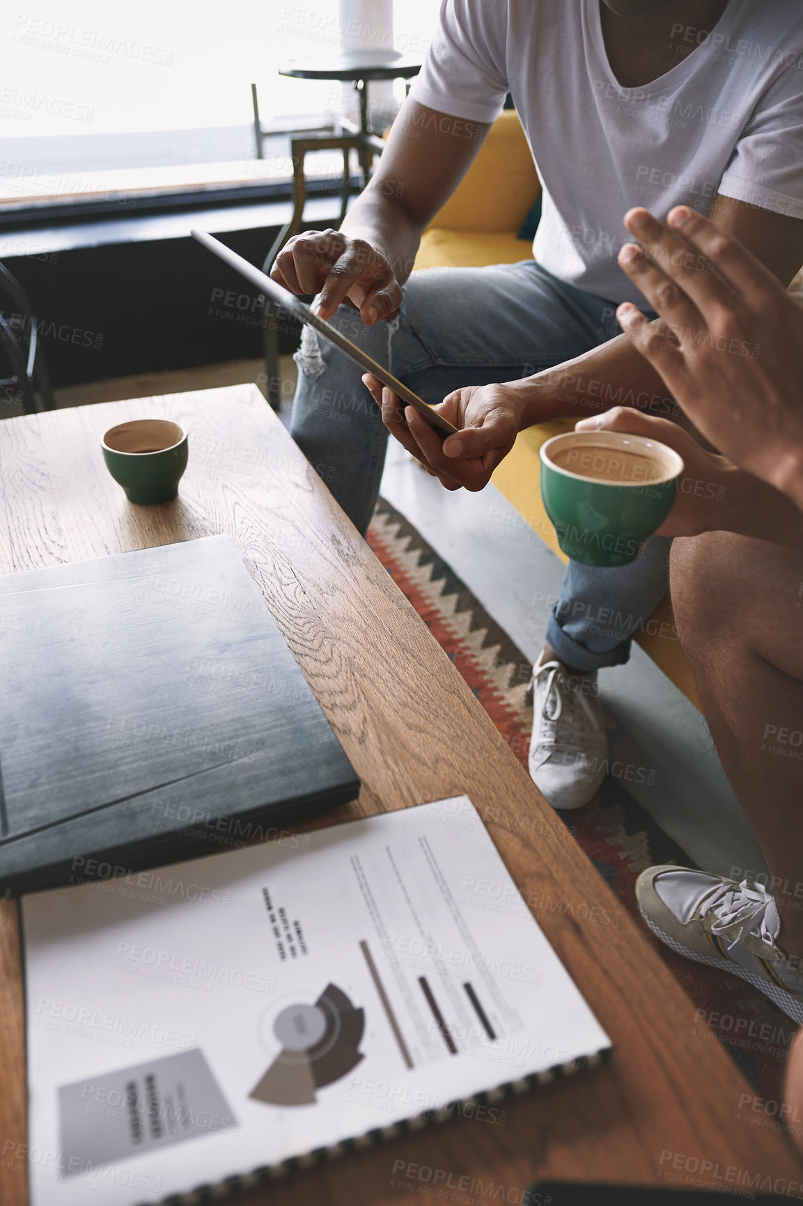 Buy stock photo Shot of two young men doing business while sitting together in a coffee shop