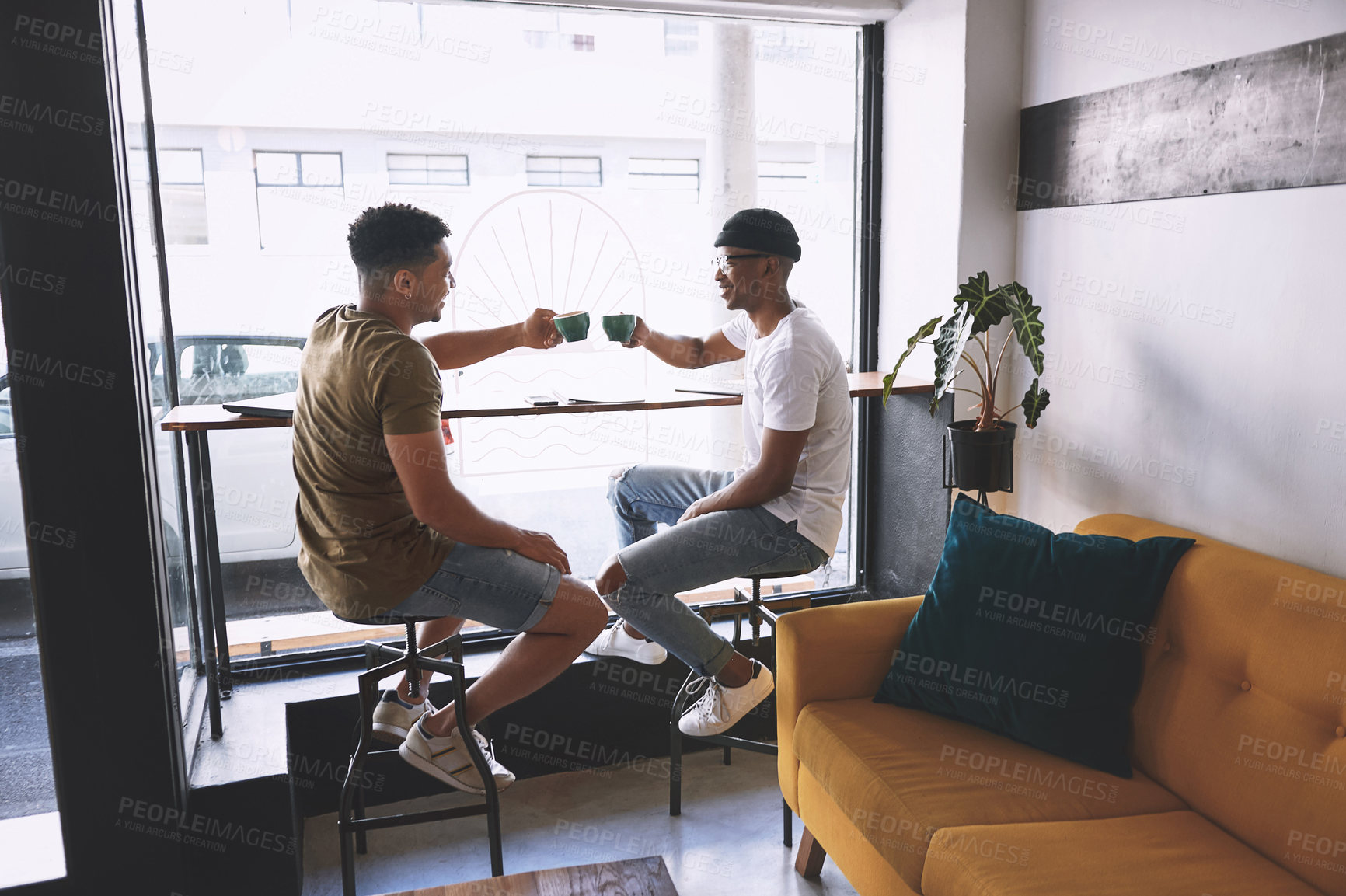 Buy stock photo Shot of two young men having coffee together in a cafe