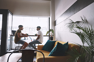 Buy stock photo Shot of two young men talking while having coffee together in a cafe