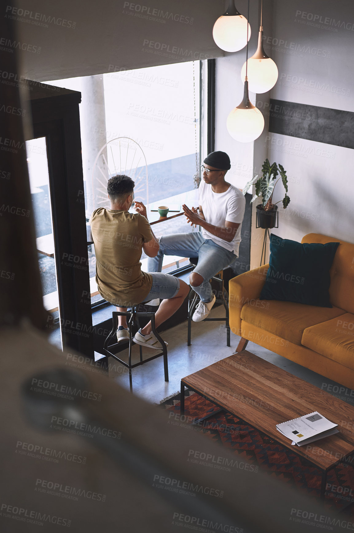 Buy stock photo Shot of two young men talking while having coffee together in a cafe