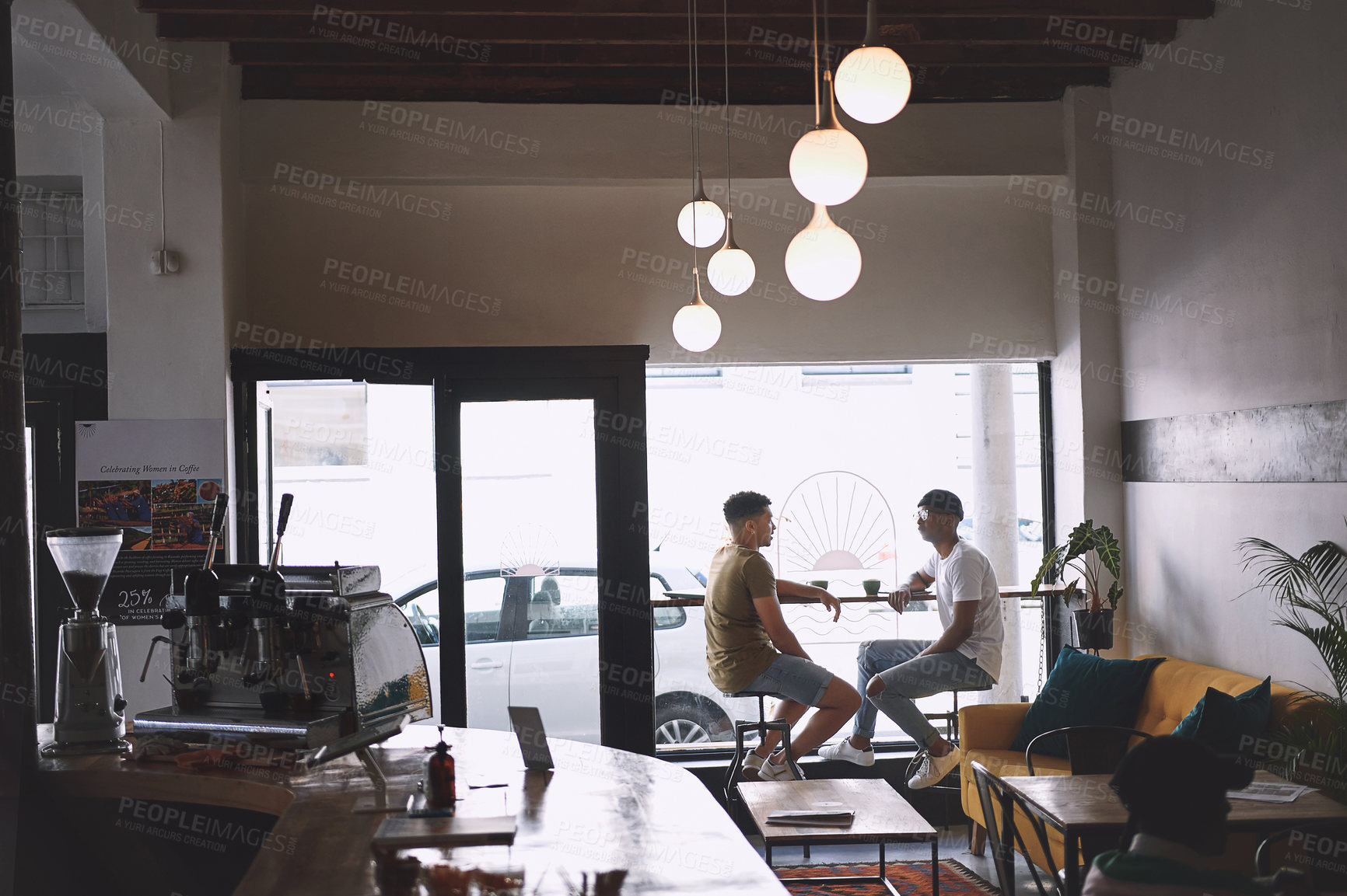 Buy stock photo Shot of two young men talking while having coffee together in a cafe