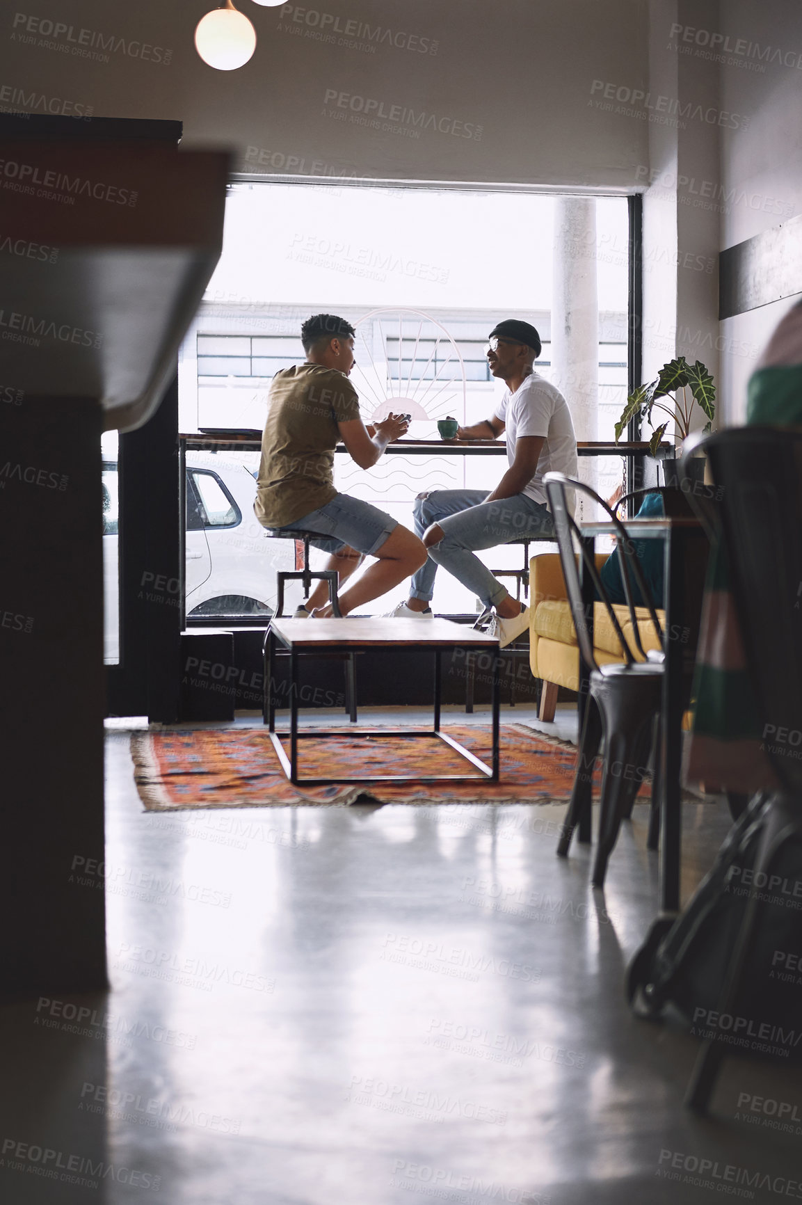 Buy stock photo Shot of two young men talking while having coffee together in a cafe