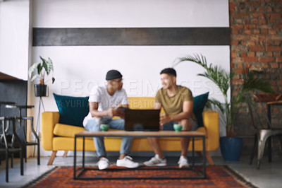 Buy stock photo Shot of two men using a laptop while sitting together in a coffee shop