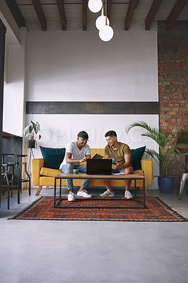 Buy stock photo Shot of two men using a laptop and a digital tablet while having coffee together