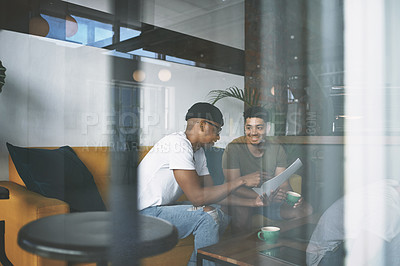 Buy stock photo Shot of two young men doing business while sitting together in a coffee shop