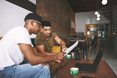 Buy stock photo Shot of two young men discussing business while sitting together in a coffee shop