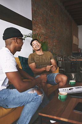Buy stock photo Shot of two men laughing while sitting together in a coffee shop