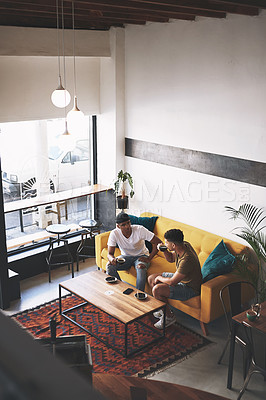 Buy stock photo Shot of two young men sitting together in a coffee shop
