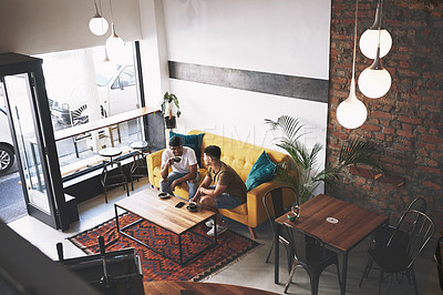 Buy stock photo Shot of two young men sitting together in a coffee shop