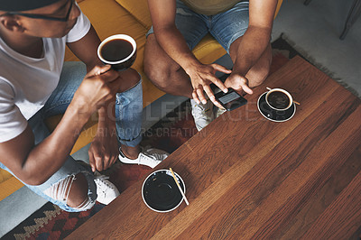 Buy stock photo Shot of men discussing something on a cellphone while sitting together in a coffee shop