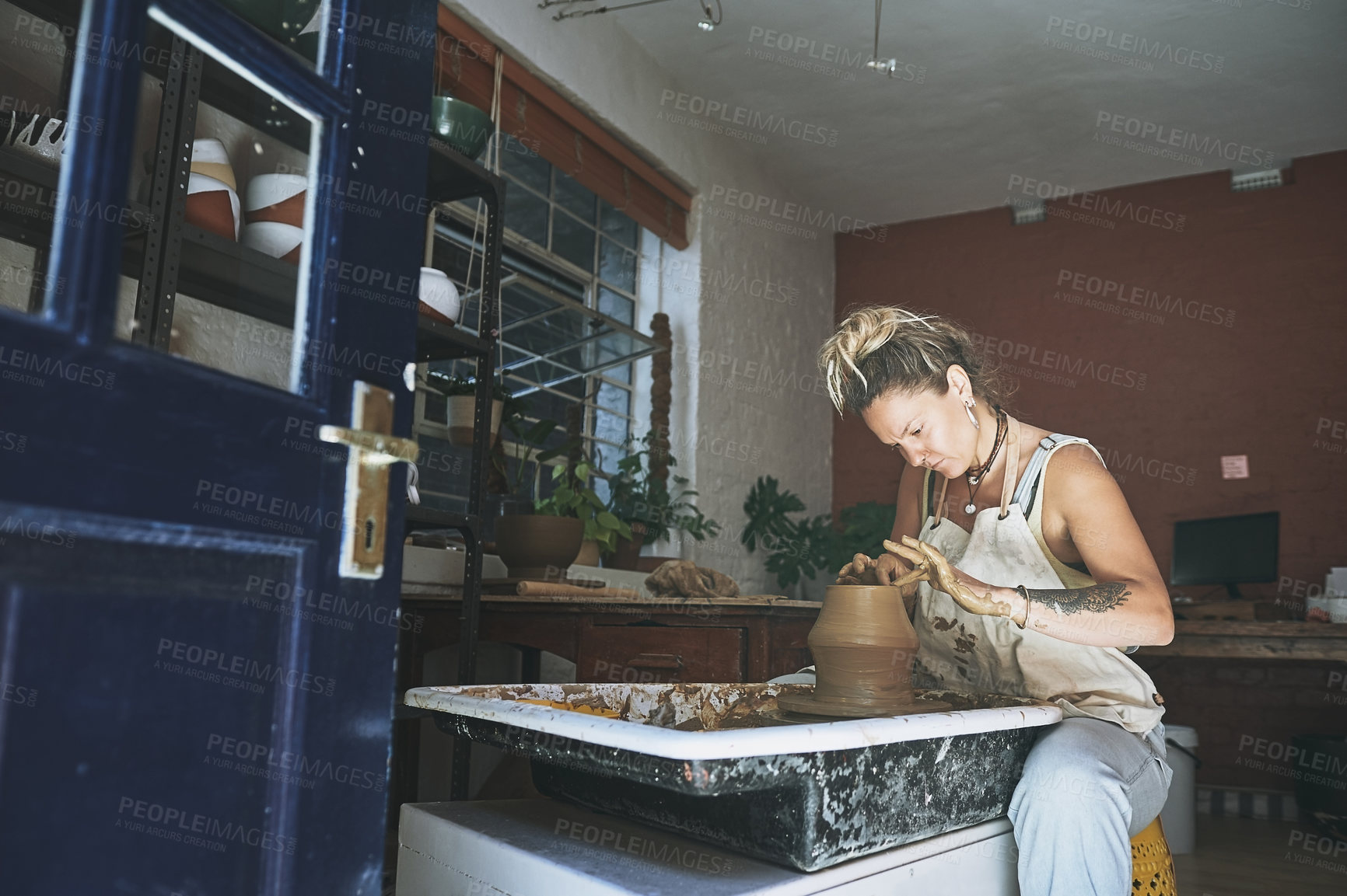 Buy stock photo Shot of a young woman working with clay in a pottery studio
