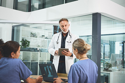 Buy stock photo Shot of a mature doctor leading a discussion with his colleagues in a hospital