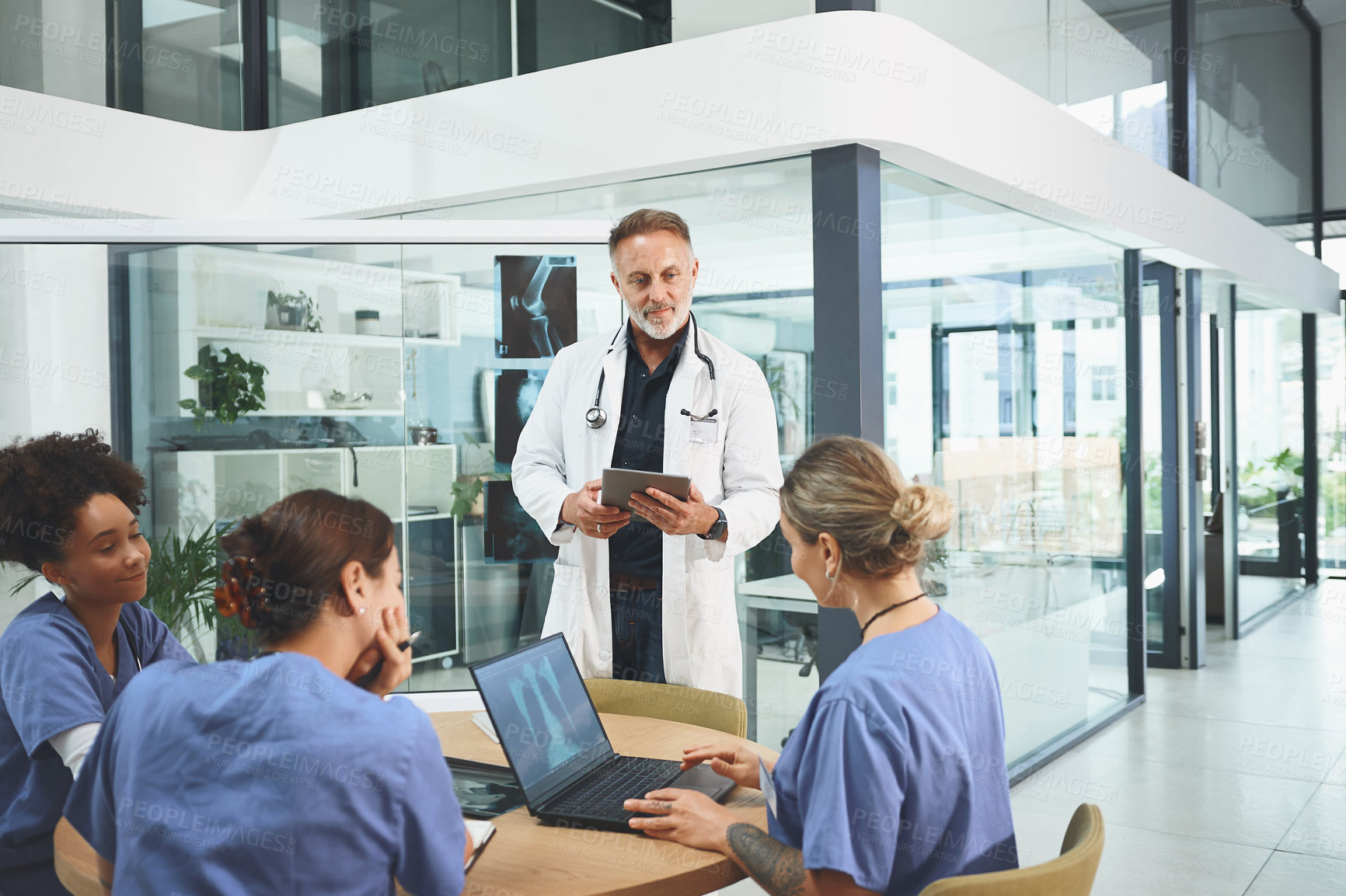 Buy stock photo Shot of a mature doctor leading a discussion with his colleagues in a hospital