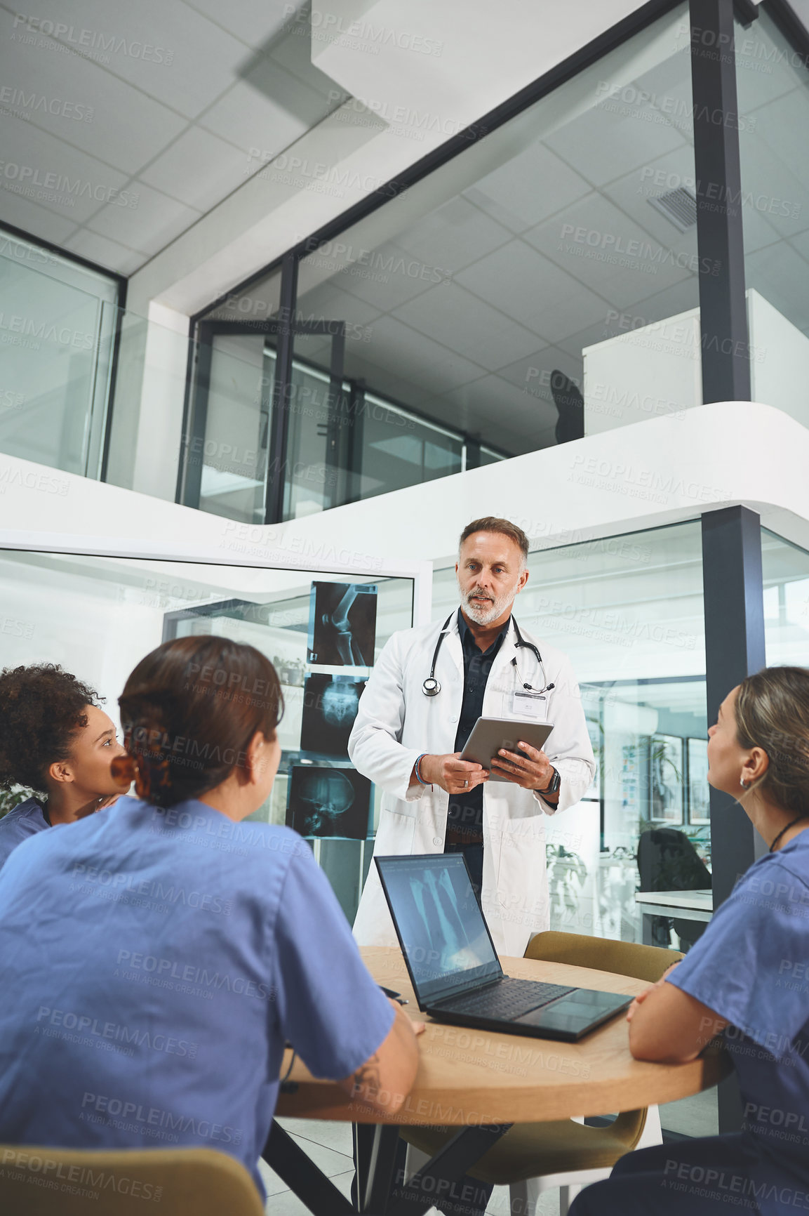 Buy stock photo Shot of a mature doctor leading a discussion with his colleagues in a hospital