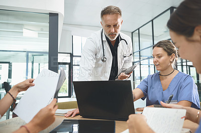 Buy stock photo Shot of a team of doctors using a laptop during a meeting in a hospital