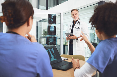 Buy stock photo Shot of a mature doctor analysing x-rays with his colleagues during a meeting in a hospital