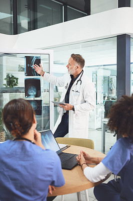 Buy stock photo Shot of a mature doctor analysing x-rays with his colleagues during a meeting in a hospital