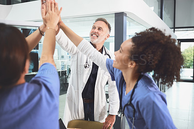 Buy stock photo Shot of a team of doctors joining their hands together in a huddle in a hospital