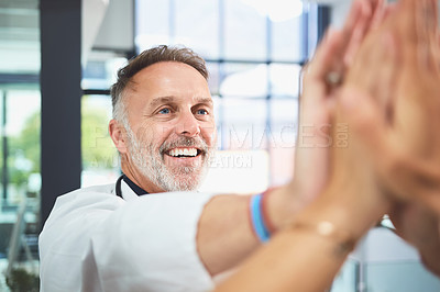 Buy stock photo Shot of a mature doctor giving his colleagues a high five in a hospital