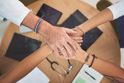 Buy stock photo Closeup shot of a team of doctors joining their hands together in a huddle in a hospital