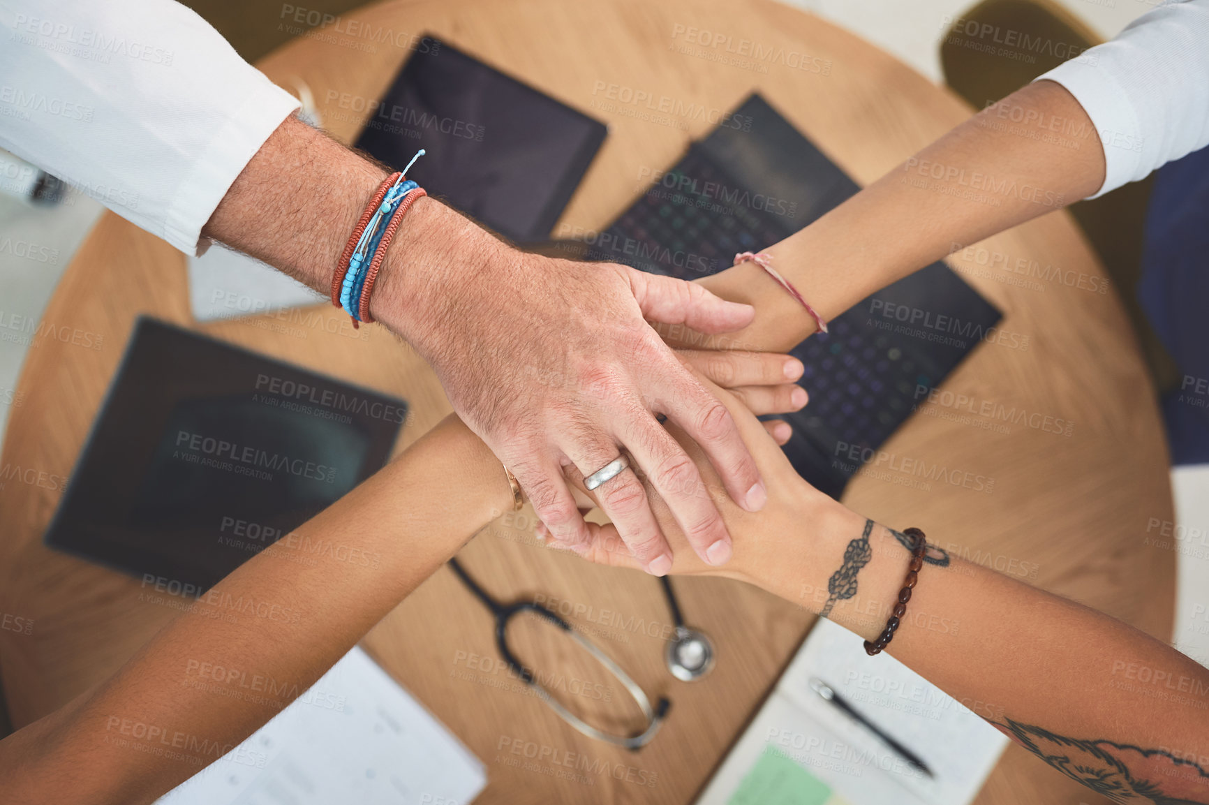 Buy stock photo Closeup shot of a team of doctors joining their hands together in a huddle in a hospital