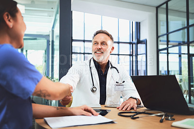 Buy stock photo Shot of doctors shaking hands during a meeting in a hospital