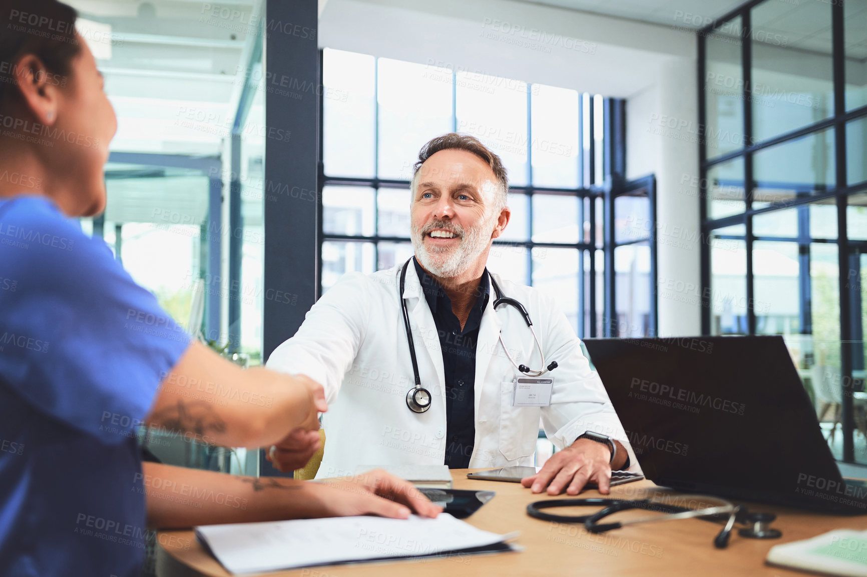 Buy stock photo Shot of doctors shaking hands during a meeting in a hospital