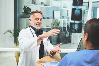 Buy stock photo Shot of a mature doctor having a discussion with a colleague in a hospital