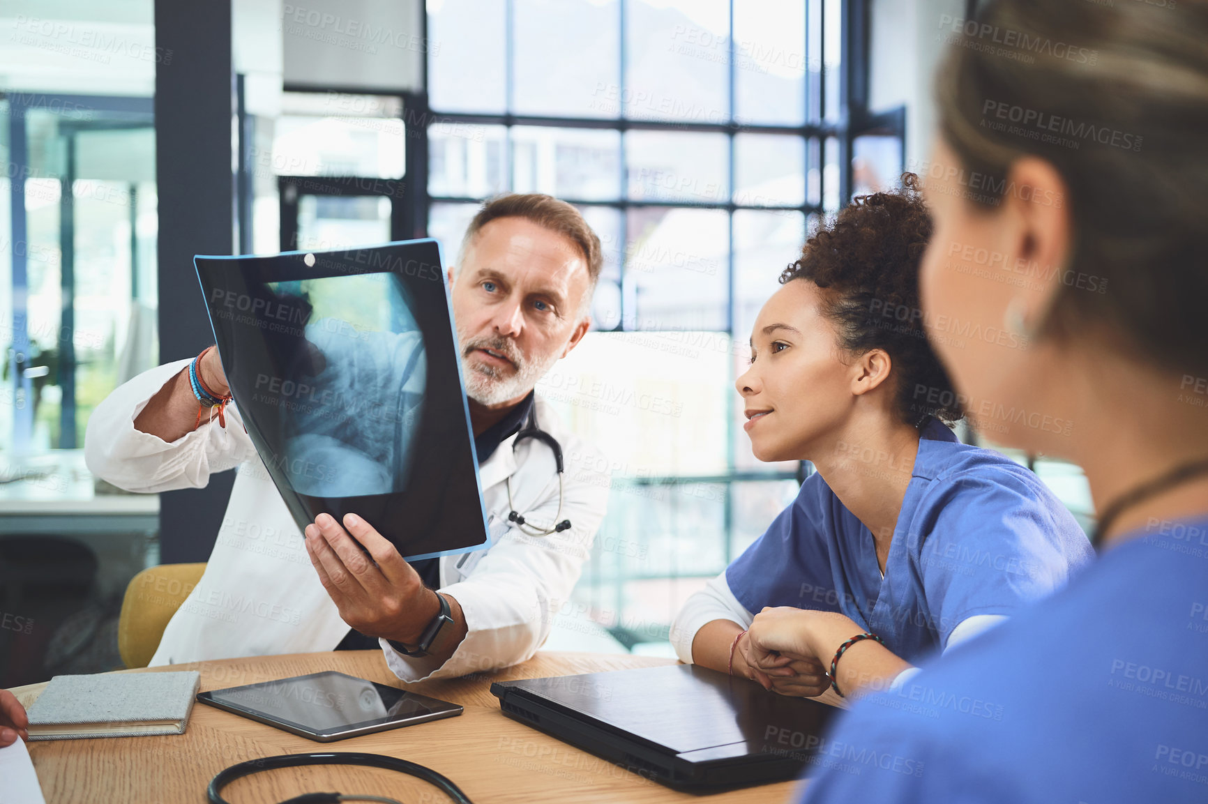 Buy stock photo Shot of a team of doctors analysing x-rays during a meeting in a hospital
