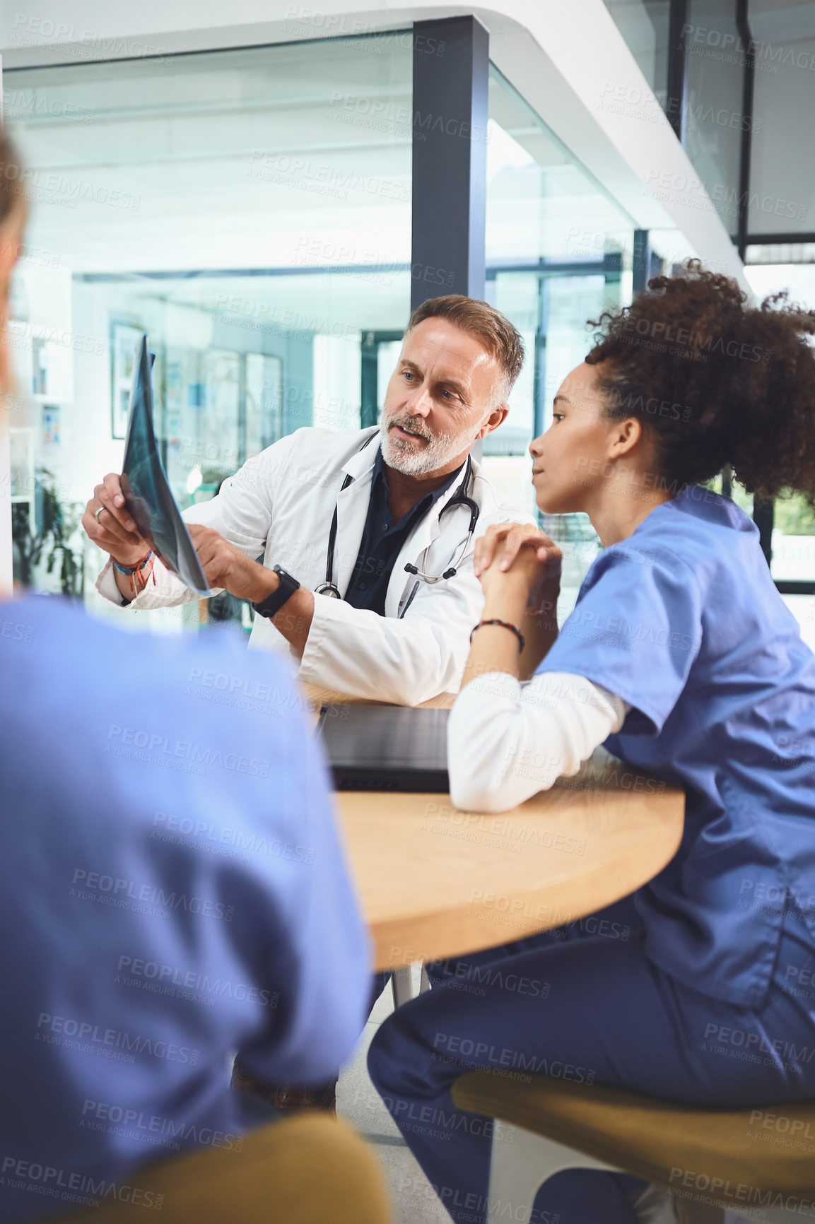 Buy stock photo Shot of a team of doctors analysing x-rays during a meeting in a hospital