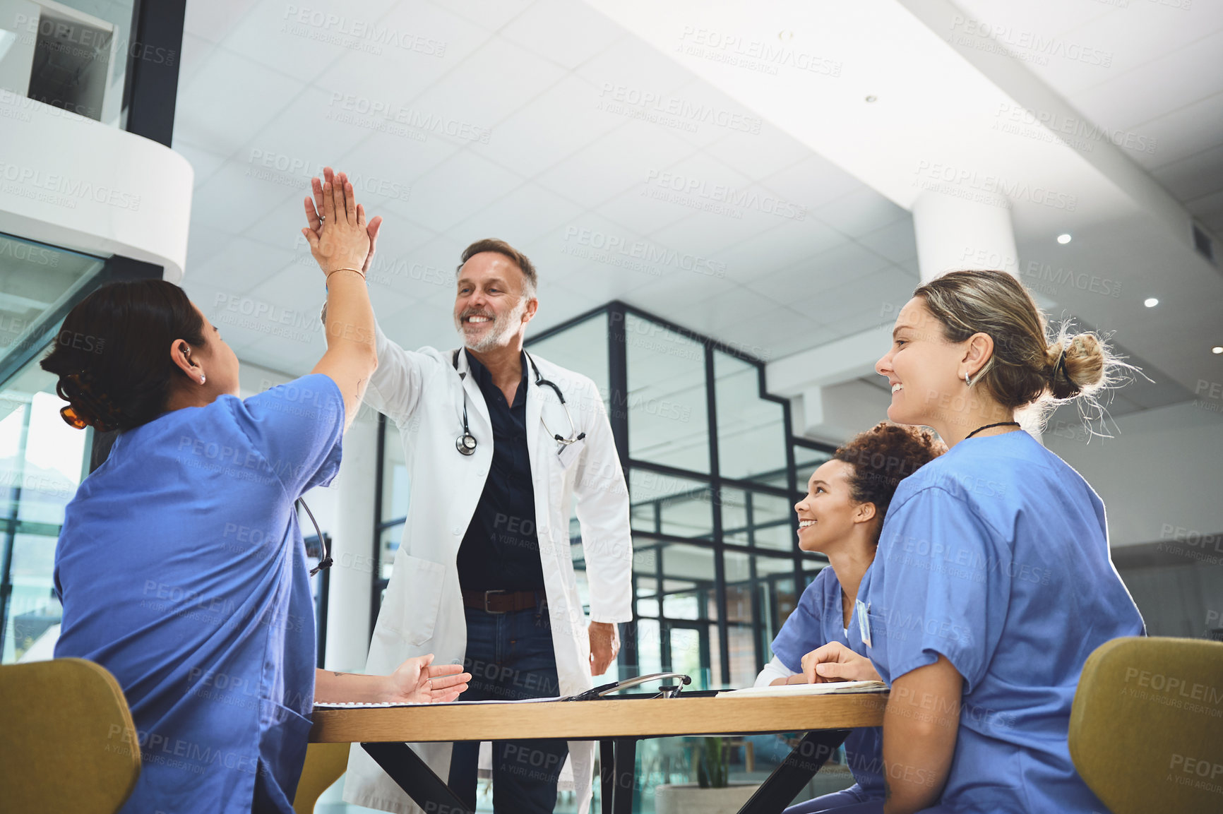 Buy stock photo Shot of a team of doctors giving each other a high five in a hospital