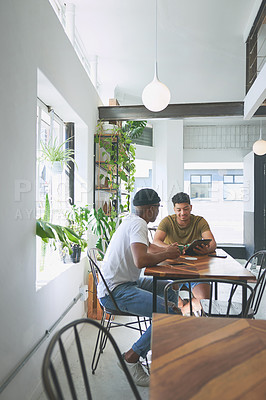 Buy stock photo Full length shot of two handsome friends sitting together and using a tablet during a discussion in a coffeeshop