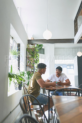 Buy stock photo Full length shot of two handsome friends sitting together and having a discussion in a coffeeshop