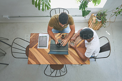 Buy stock photo High angle shot of two unrecognizable friends sitting together and using technology during a discussion in a coffeeshop