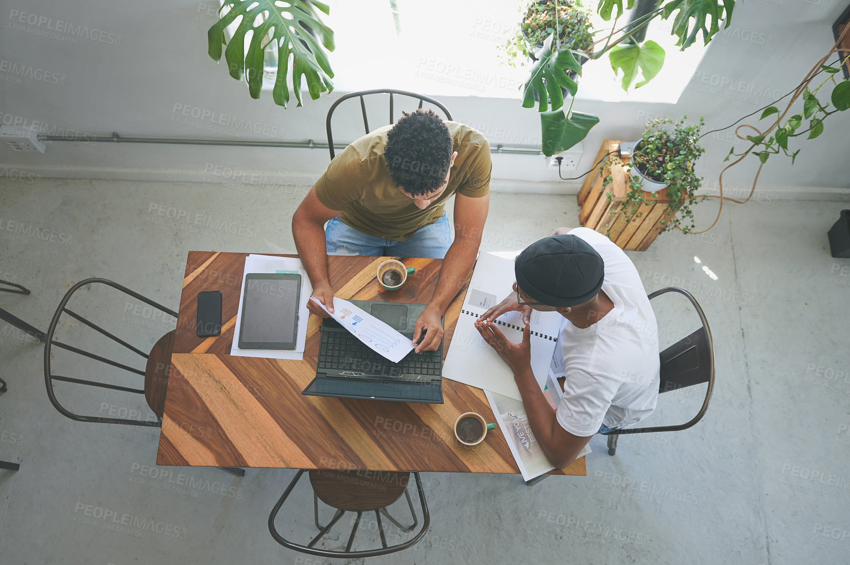 Buy stock photo High angle shot of two unrecognizable friends sitting together and using technology during a discussion in a coffeeshop