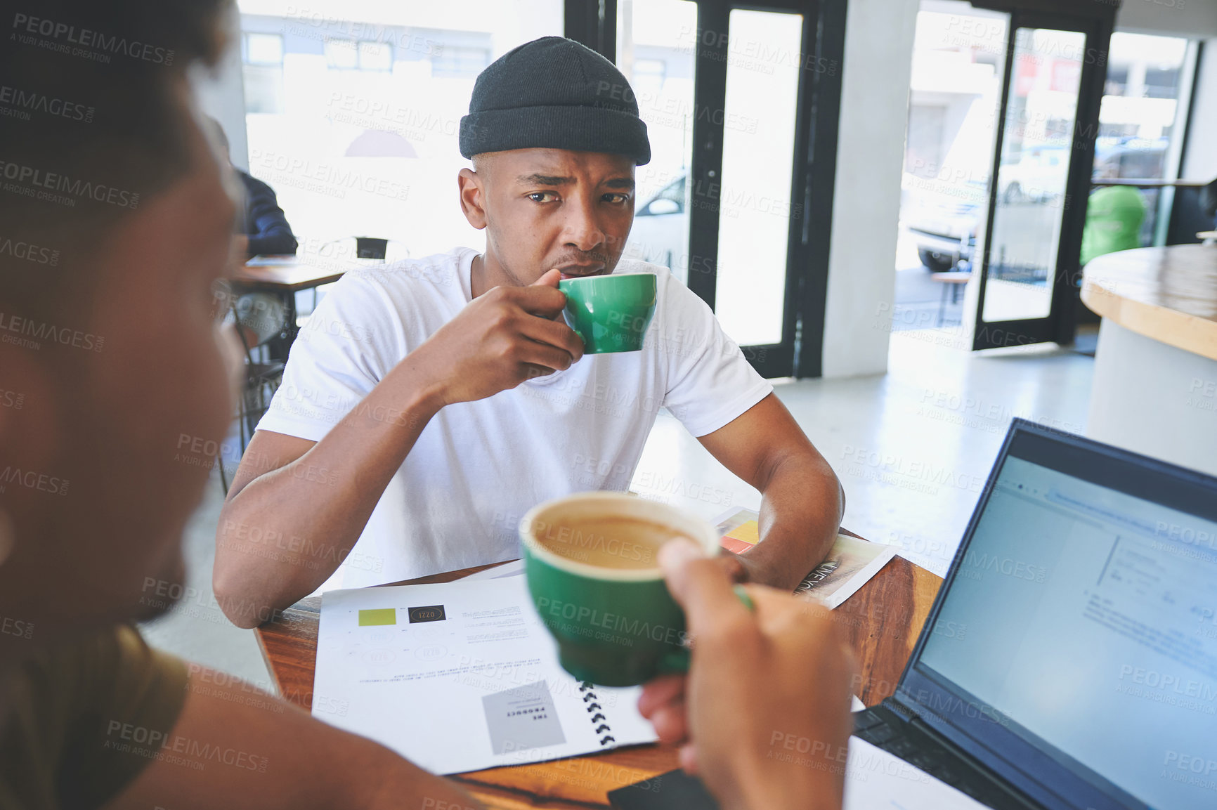 Buy stock photo Cropped shot of two handsome friends sitting together in a coffeeshop and having a discussion