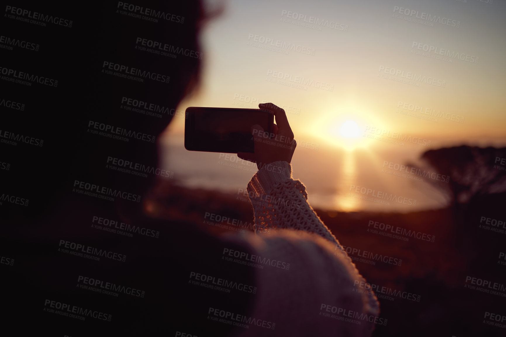 Buy stock photo Hiking, photography and woman with phone at sunset, nature and mountain to relax on holiday adventure. Smartphone, trekking and person with view of orange sky, ocean and memory on vacation from back