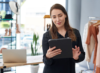 Buy stock photo Shot of a young business owner using a digital tablet in her clothing store