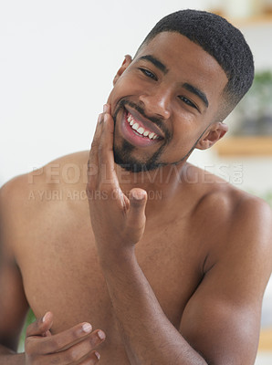 Buy stock photo Cropped shot of a handsome young man standing and applying aftershave to his skin in his bathroom