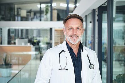Buy stock photo Cropped portrait of a handsome mature doctor standing alone in the clinic during the day