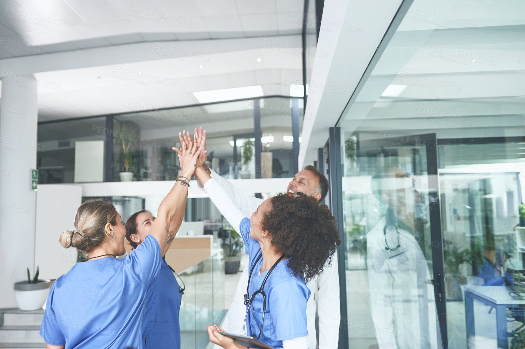 Buy stock photo Cropped shot of a diverse group of healthcare professionals standing and giving each other a high five