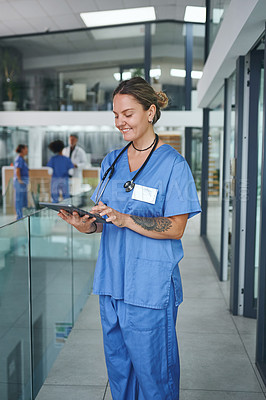 Buy stock photo Cropped shot of an attractive young nurse standing and using a digital tablet in the clinic