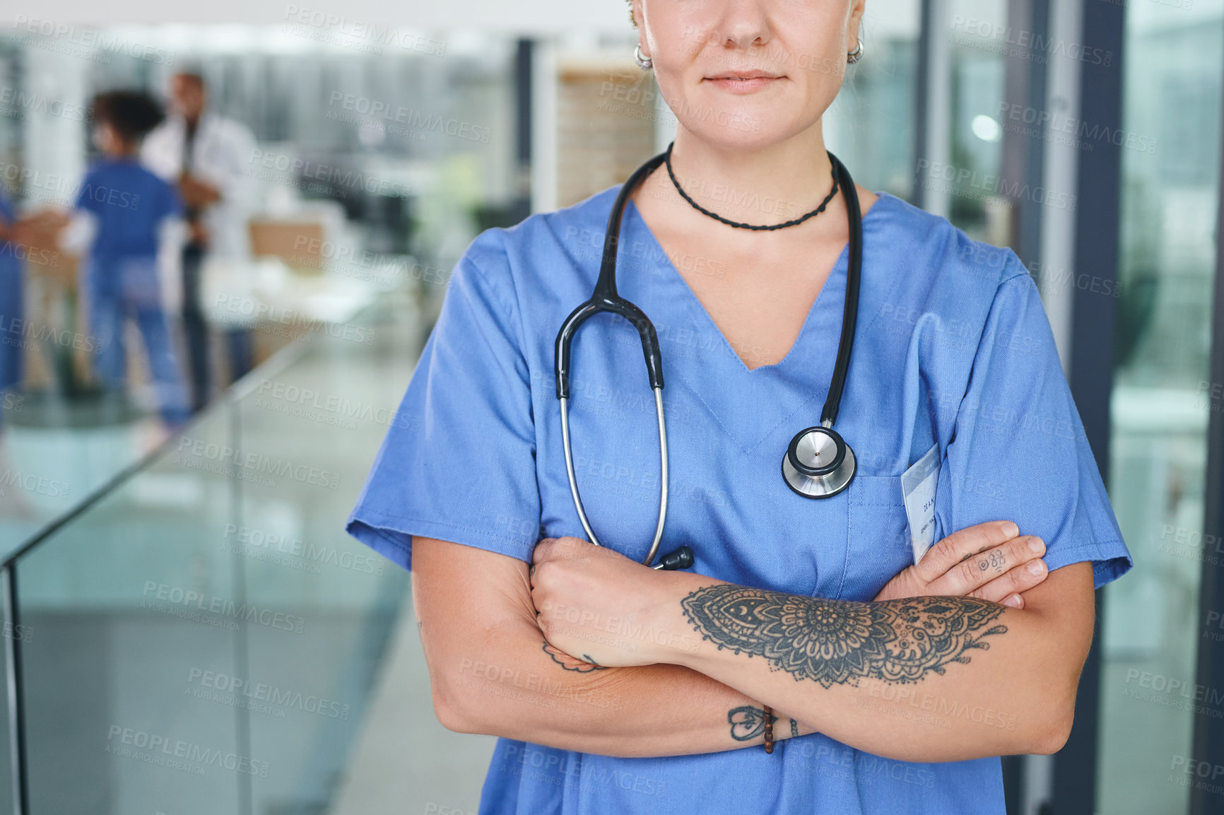 Buy stock photo Cropped shot of an unrecognizable nurse standing in the clinic during the day with her arms folded