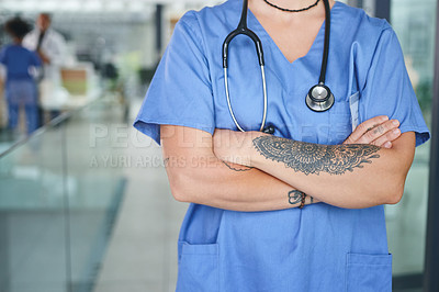 Buy stock photo Cropped shot of an unrecognizable nurse standing in the clinic during the day with her arms folded
