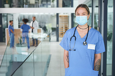 Buy stock photo Cropped portrait of an attractive young nurse wearing a face mask and standing in the clinic