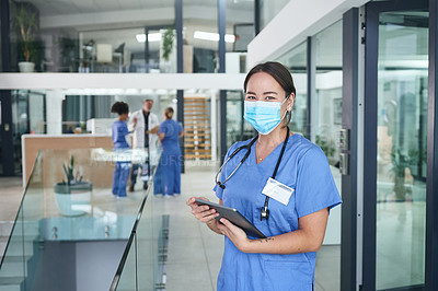 Buy stock photo Cropped portrait of an attractive young nurse standing and wearing a face mask while using a digital tablet