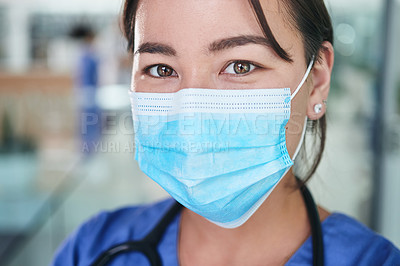 Buy stock photo Cropped portrait of an attractive young nurse wearing a face mask and standing alone in the clinic